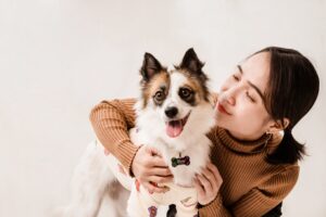 Cute dog with woman smiling and hugging, showcasing pet companionship and love.